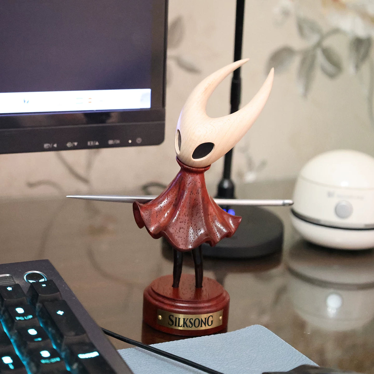 Hornet wooden figure displayed on a desk beside a monitor